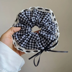 Gros plan d'un chouchou à carreaux bleus avec bordure en dentelle blanche et nœud noir