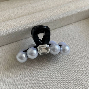 Détail d'une mini pince à cheveux avec perles élégantes et un strass rectangulaire