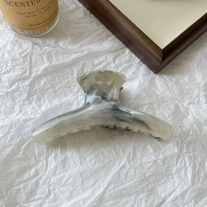 Macro detail of large marble pattern hair claw clip with acetate finish and metal spring
