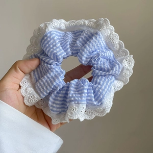 Détail d'un chouchou à rayures bleues avec une bordure en dentelle blanche brodée