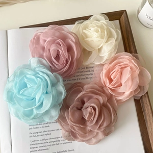 Détail de cinq barrettes fleurs en tulle colorées sur un livre pour un style français chic