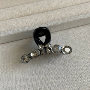 Gros plan sur la pince à cheveux noire avec cristaux gris et nœud scintillant en strass