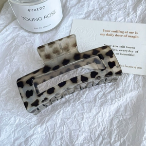 Détail d'une grande pince à cheveux léopard rectangulaire sur fond blanc esthétique