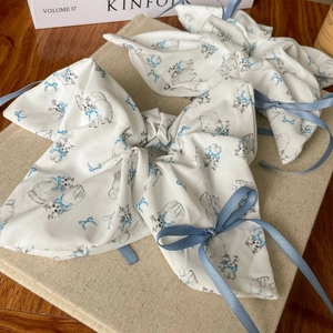 Elegant white scrunchie with cat print and long ribbon bow on neutral linen base