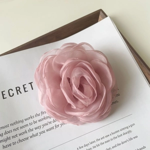 Détail d'une pince à cheveux camélia en organza rose avec des pétales translucides