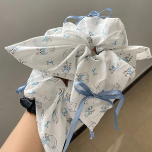 White fabric scrunchie with cat illustrations and blue ribbon bows for hair styling