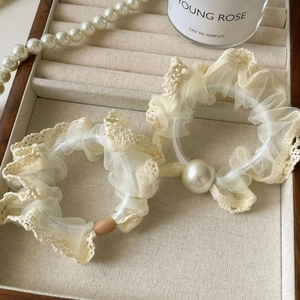 Close-up of lace hair ties with pearls and organza detail on a velvet jewelry box