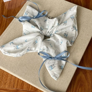 Close-up of white silk scrunchie with blue cat prints and decorative ribbon details