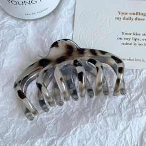 Détail d'une pince à cheveux motif léopard en acétate sur un papier blanc élégant