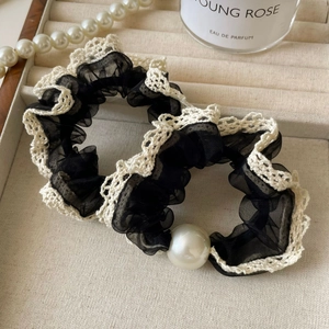Detail of elegant black organza scrunchies with white lace edges and large white pearls