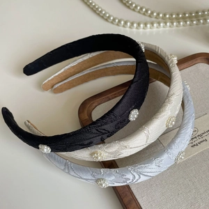 Detail view of retro floral pearl headbands in black, beige, and light blue satin fabric