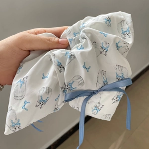 Detail of white ballet-style scrunchie with grey cat prints and a blue satin ribbon bow