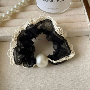Detail of black mesh hair scrunchie with white lace trim and elegant large pearl ornament