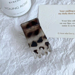 Détail d'une pince à cheveux rectangulaire motif léopard sur un support blanc chic