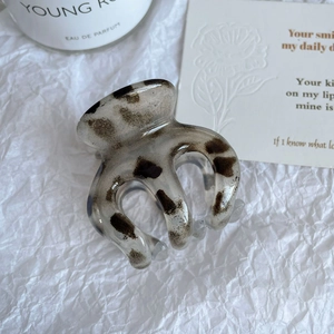 Détail d'une grande pince à cheveux motif léopard sur un fond texturé blanc