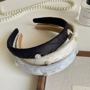 Detail of embroidered floral headbands with pearls in black, beige, and blue colors