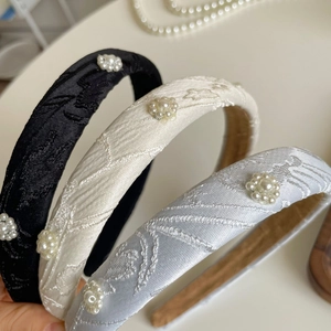 Close-up of three vintage pearl flower headbands in black, cream, and silver-grey colors
