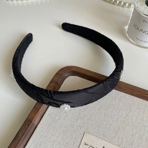 Detail of black silk headband featuring floral pearl clusters and elegant fabric texture