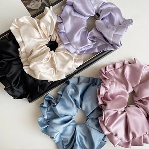 Détail de cinq chouchous en satin de couleurs avec volants plissés et texture soyeuse