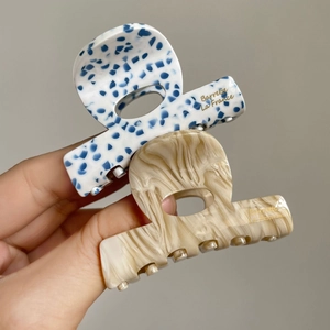 Détail de pinces à cheveux en acétate marbré avec lettrage doré Barrette La France