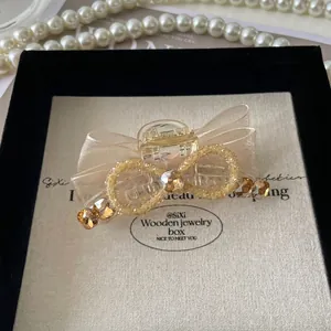 Détail d'une pince à cheveux élégante avec nœud en soie champagne et strass brillants