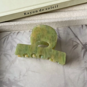 Détail d'une grande pince à cheveux en acétate avec texture marbrée verte et jaune