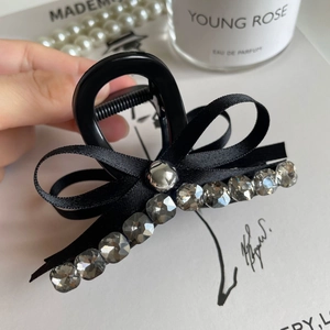 Macro view of grey hair claw clip featuring rhinestone details and satin ribbon bow decor