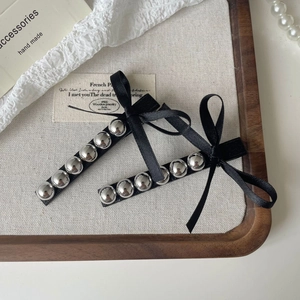 Barrettes à cheveux avec nœud en ruban noir et perles argentées sur plateau en lin