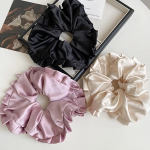 Trois grands chouchous en satin noir, crème et rose avec des bords à volants plissés