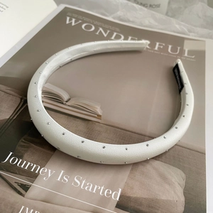Elegante witte satijnen haarband met zilveren studs en een handgemaakt label erop