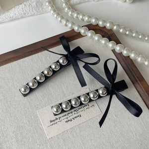 Barrettes vintage noires avec perles argentées et nœud élégant sur fond en lin