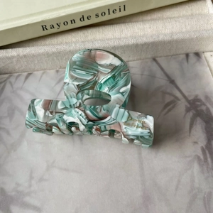 Détail macro de la pince à cheveux en acétate marbré avec lettrage doré Barrette