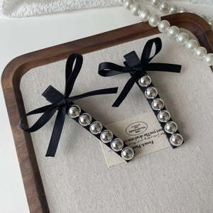 Paire de barrettes à nœuds en satin noir avec perles argentées sur un plateau