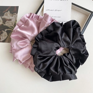 Gros plan de chouchous en satin rose et noir avec texture plissée sur fond blanc propre