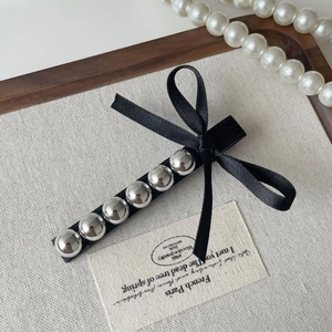 Détail de la barrette vintage à perles grises et nœud papillon sur fond de lin chic