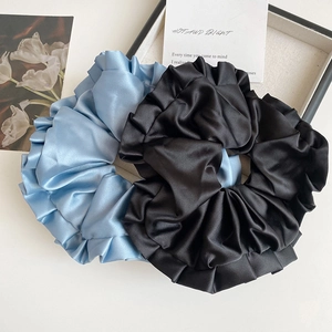 Gros plan de chouchous en satin bleu marine et noir avec une texture soyeuse plissée