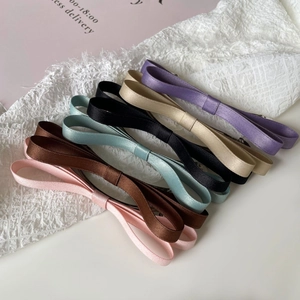 Close-up of six colorful satin bow hair clips in pink, brown, mint green, and black