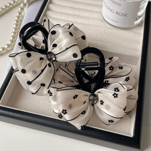 Elegant polka dot and floral hair claws with faceted gemstones on a jewelry tray