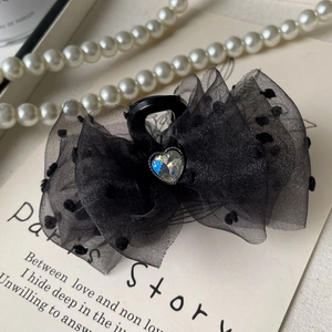 Detail of black polka dot tulle bow hair claw with a sparkling heart-shaped rhinestone