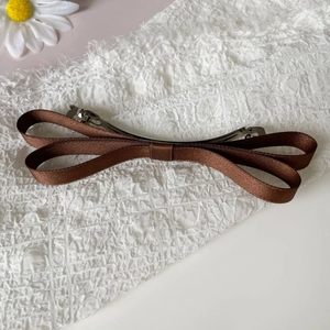 Detail of the elegant dark brown satin ribbon bow hair clip with silver metal spring fastener