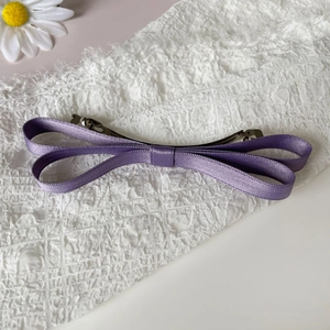 Detailed view of the purple satin bow hair clip with a silver metal spring fastener
