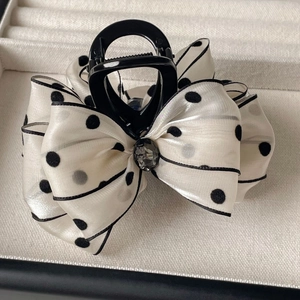 Detailed macro view of polka dot satin bow hair claw with a dark grey central rhinestone