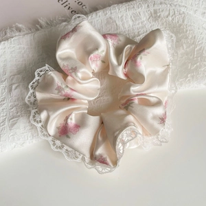 Détail d'un chouchou en soie à fleurs roses avec bordure en dentelle blanche