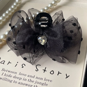 Detailed view of black polka dot tulle bow hair claw with a crystal heart rhinestone