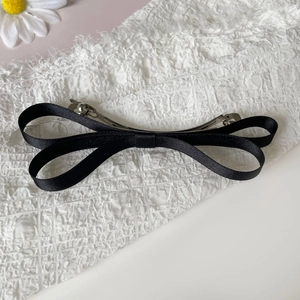 Detailed back view of a black satin bow hair clip with double silver metal snap fasteners