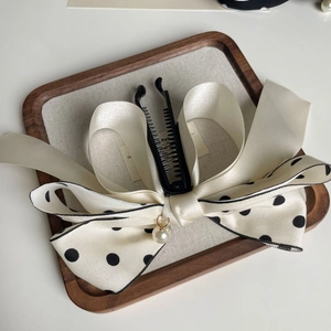 Détail du nœud papillon en satin ivoire avec pois noirs et pendentif perle blanche