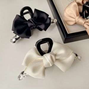 Detailed view of satin bow hair clips with rhinestones in black, cream and champagne