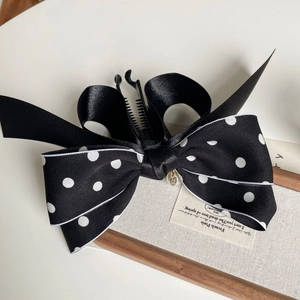 Détail d'une barrette à nœud en satin à pois avec un pendentif en perle élégante