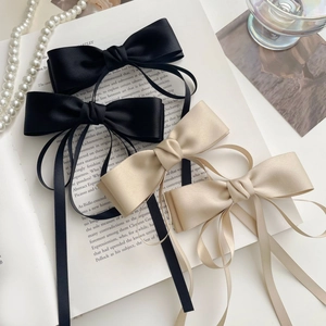 Détail de barrettes à nœuds en satin élégantes avec de longs glands noirs et champagne
