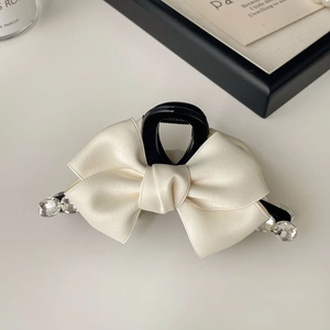 Detail of elegant cream satin ribbon bow hair claw with sparkling rhinestones decoration